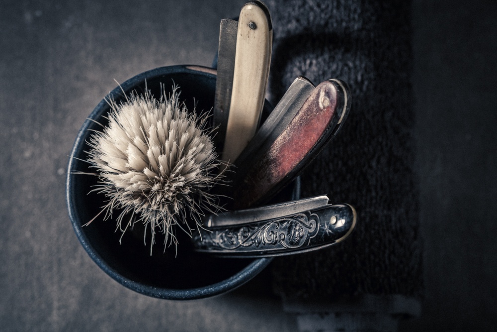 shaving brush with 3 straight razors in a pot