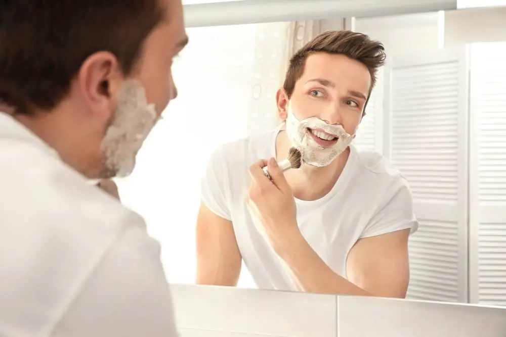 man applying shaving foam on his face with a shaving brush